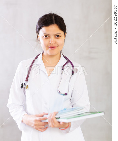 Smiling female medical student holding workbooks with lecture notes 102299587