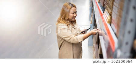 Female customer. Plus size female warehouse worker inspecting box of products by smart phone while working in large warehouse Female customer. Plus size female warehouse worker inspecting box of products by smart phone while working in large warehouse 102300964