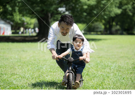 自転車の練習をで走る親子 新緑の公園でパパと息子 自転車の練習をで走る親子 新緑の公園でパパと息子 102301695