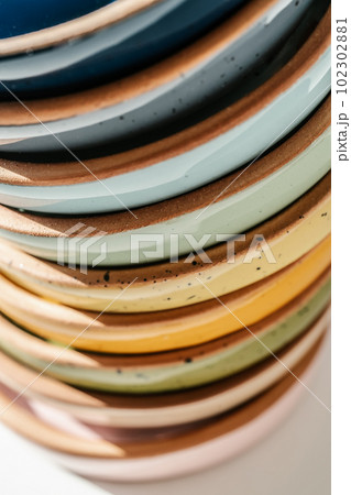A large stack of ceramic cups in pastel colors. 102302881