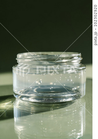 Transparent gel in a jar on a green background. Transparent gel in a jar on a green background. 102302920