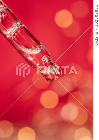 Pipette with serum on a red holiday background with bokeh. 102302951