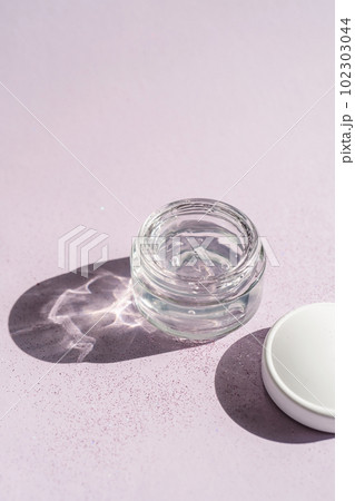 Transparent gel in a jar on a lilac background. 102303044