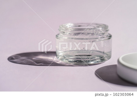Transparent gel in a jar on a lilac background. Transparent gel in a jar on a lilac background. 102303064