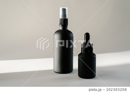 Black cosmetic bottles on a background flooded with sunlight. Black cosmetic bottles on a background flooded with sunlight. 102303208