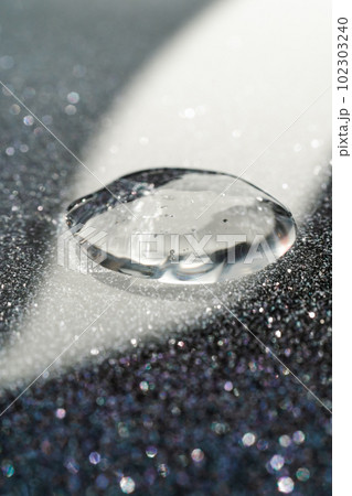 A drop of cosmetic gel on a black shining background. A drop of cosmetic gel on a black shining background. 102303240