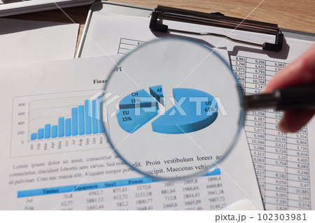 Woman looks at statistics paper through magnifier glass 102303981