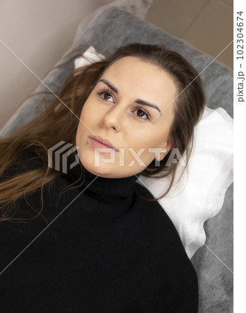 Young Beautiful Woman Having Permanent Make Up Tattoo On Eyebrows In Beauty Salon, Lying On Couch. Cosmetic Procedure. Healed Eyebrows. Long Lasting Liner. Skin Micropigmentation. Vertical Plane 102304674