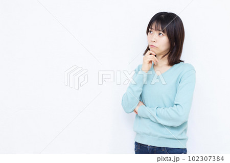 白い背景の前で真剣に悩んでいる30代の女性 白い背景の前で真剣に悩んでいる30代の女性 102307384