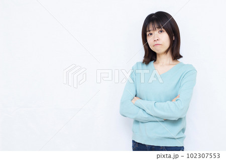 白い背景の前で腕を組み困っている30代の女性 白い背景の前で腕を組み困っている30代の女性 102307553