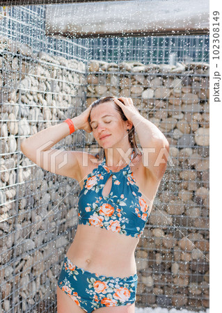 Beautiful woman, wearing swimsuit, taking shower in outdoor in her summer holidays 102308149