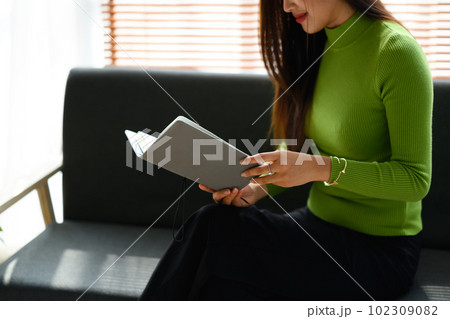 Peaceful young woman sitting on couch and reading book. People, leisure and lifestyle concept Peaceful young woman sitting on couch and reading book. People, leisure and lifestyle concept 102309082