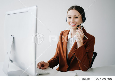 Serious call center operator in wireless headset talking with customer, woman in headphones with microphone consulting client on phone in customer support service in office center.. Serious call center operator in wireless headset talking with customer, woman in headphones with microphone consulting client on phone in customer support service in office center.. 102309760