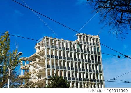 Demolition of the old building with sloopkraan against blue clouds sky. 102311399
