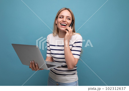 smiling funny young woman student with a laptop in her hands laughing while chatting on the phone on 102312637