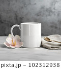 Coffee mug, a white cup on a table with a cupcake and flowers. Styled photo, product mockup 102312938
