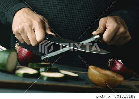 man steels a kitchen knife 102313198