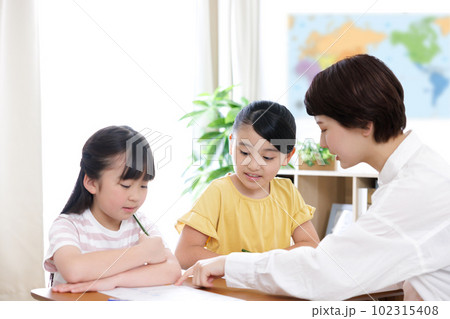 勉強する小学生の女の子と大学生の女性 勉強する小学生の女の子と大学生の女性 102315408