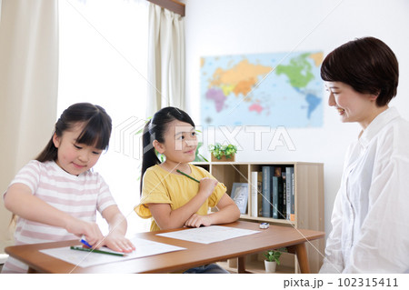 勉強する小学生の女の子と大学生の女性 勉強する小学生の女の子と大学生の女性 102315411