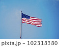 ニューヨークの青空に掲げられるアメリカ国旗 102318380