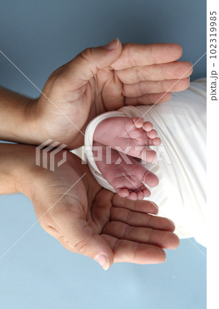 Tiny foot of a newborn baby. Soft legs of a newborn in a white blanket. Close up the toes, heels and feet of a newborn baby. Studio macro photography baby feet on a white background. 102319985