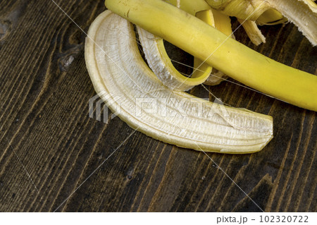 peeled ripe yellow bananas on a wooden board 102320722