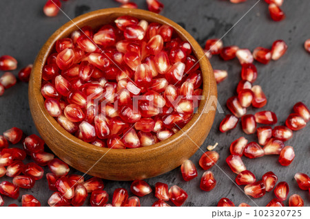 Red ripe pomegranate seeds with lots of juice in a wooden bowl Red ripe pomegranate seeds with lots of juice in a wooden bowl 102320725