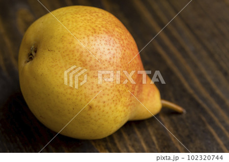 A yellow ripe pear with a red side on the table 102320744