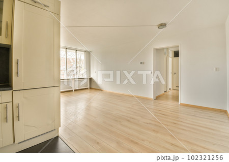 an empty living room with wood flooring and white cupboards on either side of the room, there is a tv mounted above an empty living room with wood flooring and white cupboards on either side of the room, there is a tv mounted above 102321256