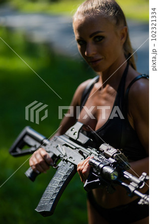 Caucasian woman in bikini with machine gun outdoors. Caucasian woman in bikini with machine gun outdoors. 102321334