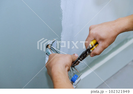 Electrician installing new current socket working safely in new house construction site Electrician installing new current socket working safely in new house construction site 102321949