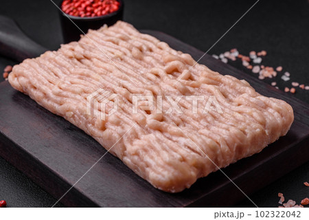 Fresh minced chicken with salt, spices and herbs on a wooden cutting board Fresh minced chicken with salt, spices and herbs on a wooden cutting board 102322042