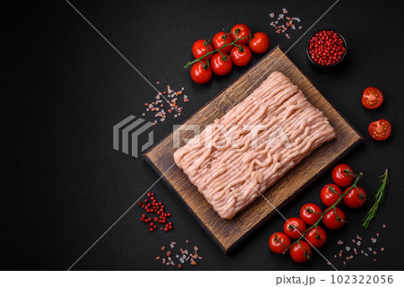 Fresh minced chicken with salt, spices and herbs on a wooden cutting board 102322056