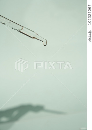 Natural medicine, cosmetic research. The concept of skin care and its analysis. Dermatology. With space to copy. Laboratory pipette with a drop of serum, oil, cosmetics. High quality photo 102325067