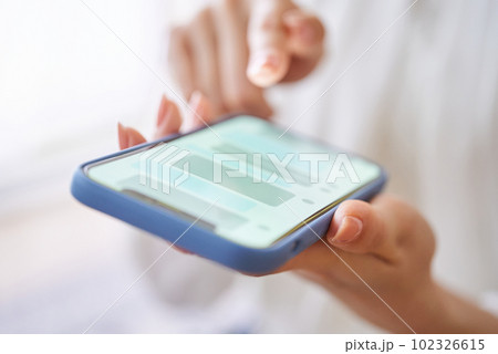 スマートフォンでメッセージのやりとりをする女性の手元 スマートフォンでメッセージのやりとりをする女性の手元 102326615