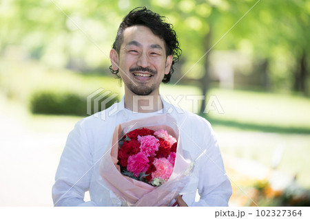 母の日や記念日に贈り物をする男性と花束　アップ 102327364