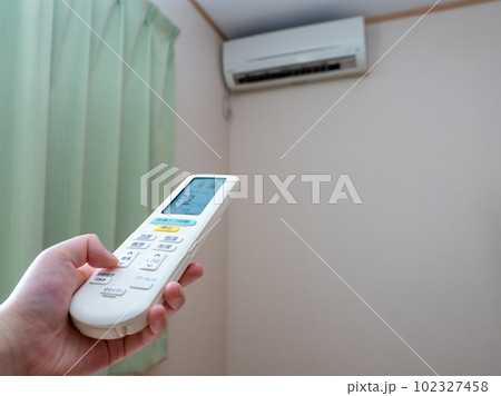 エアコンのリモコンで温度設定をする女性の手（設定28℃　送風口開） 102327458