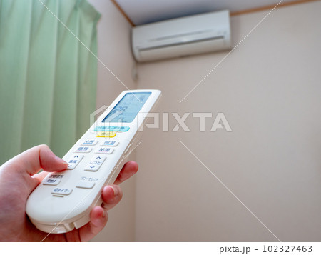 エアコンのリモコンで温度設定をする女性の手（設定28℃　送風口閉） 102327463