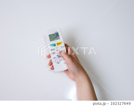 エアコンのリモコンで冷房温度設定をする女性の手(設定26℃) エアコンのリモコンで冷房温度設定をする女性の手(設定26℃) 102327649