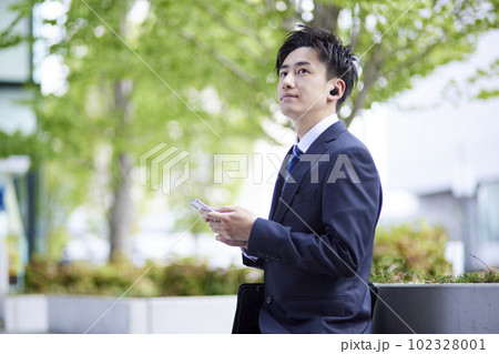 ワイヤレスイヤホンとスマートフォンを使う日本人男性会社員 ワイヤレスイヤホンとスマートフォンを使う日本人男性会社員 102328001