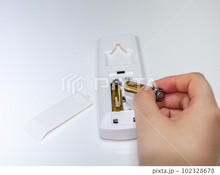 リモコンの電池交換をする女性の手（単4電池） 102328678