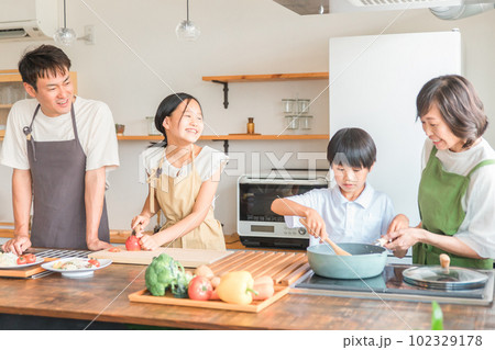 家のキッチンで子供と一緒に料理・クッキング・お手伝いする子供と夫婦・親子・家族 102329178