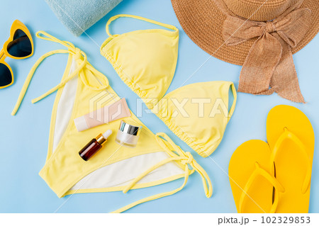 Top view of yellow bikini and cream bottle, sandals, sunglasses with beach accessories background. Top view of yellow bikini and cream bottle, sandals, sunglasses with beach accessories background. 102329853