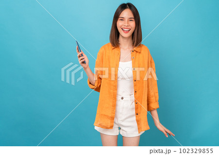 Beautiful Asian woman holding smartphone and smiling on blue background. Beautiful Asian woman holding smartphone and smiling on blue background. 102329855