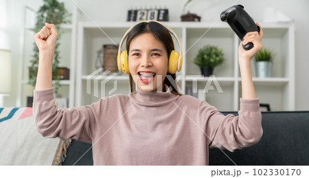 woman playing online game with fists clenched celebrating victory expressing success to win. woman playing online game with fists clenched celebrating victory expressing success to win. 102330170