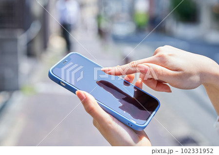 街角でスマートフォンを使う女性の手元 街角でスマートフォンを使う女性の手元 102331952