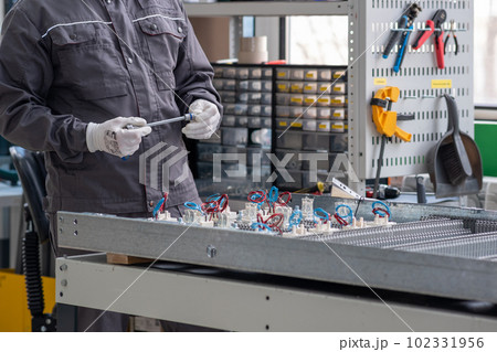 worker operates an automatic production line (PCB printer machine) in a workshop 102331956