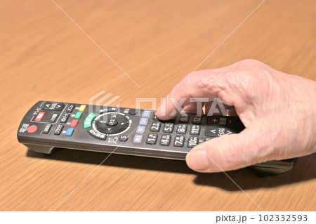 テレビのリモコンを操作する高齢女性の指先 102332593