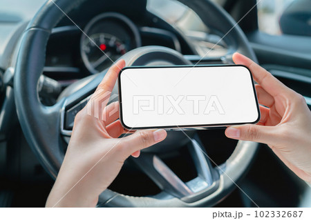 Woman sitting in a private car and hand holding smartphone mockup of blank screen. 102332687