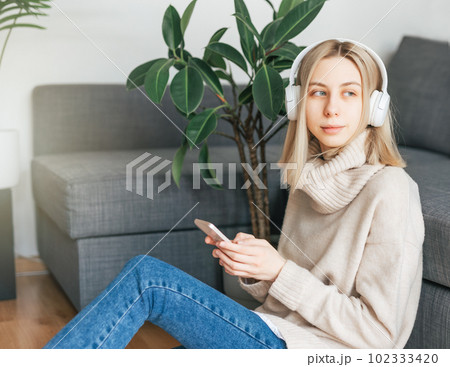 Young caucasian woman relaxes at home with music 102333420